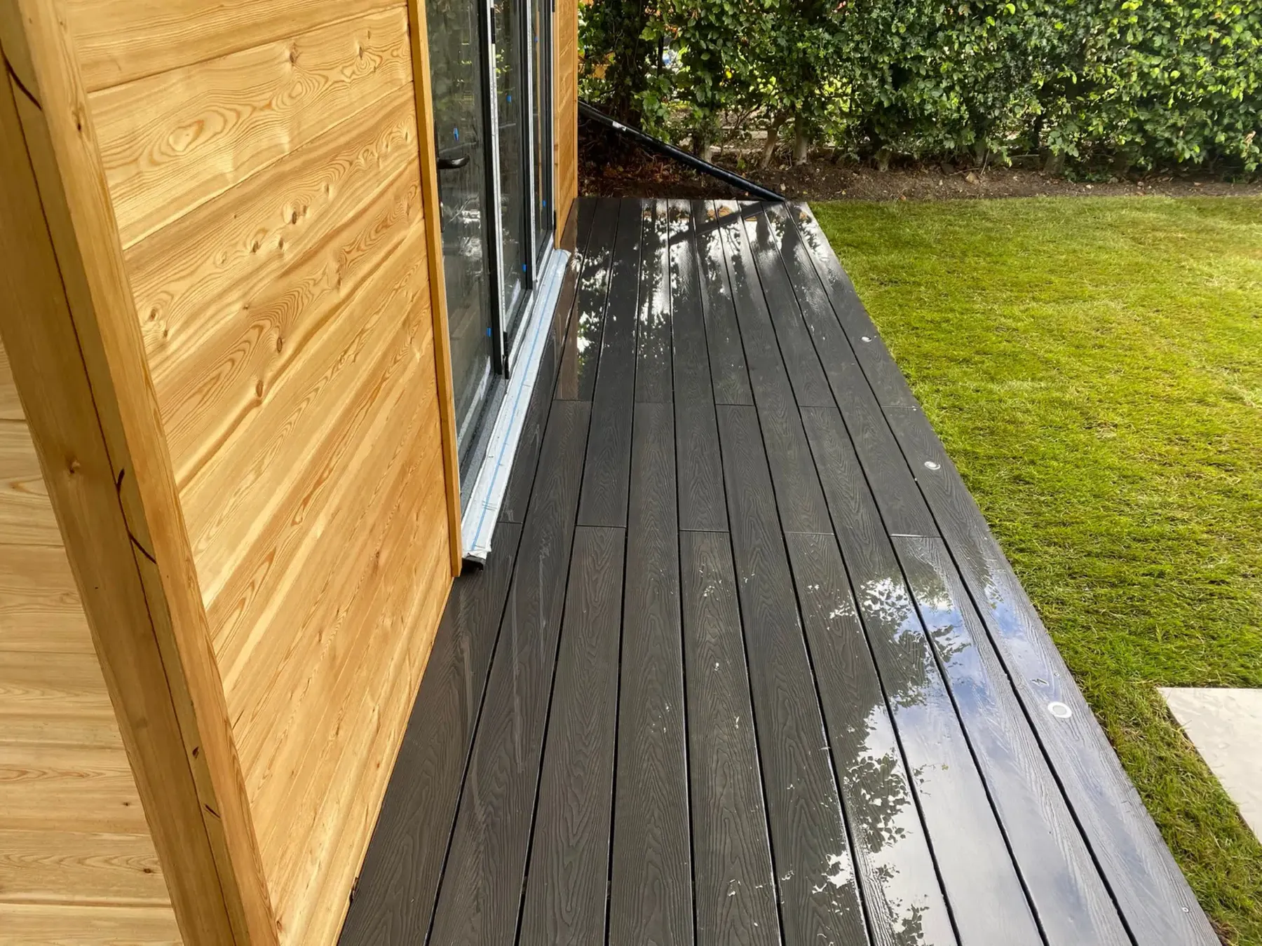 Composite decking meeting a cedar clad garden room