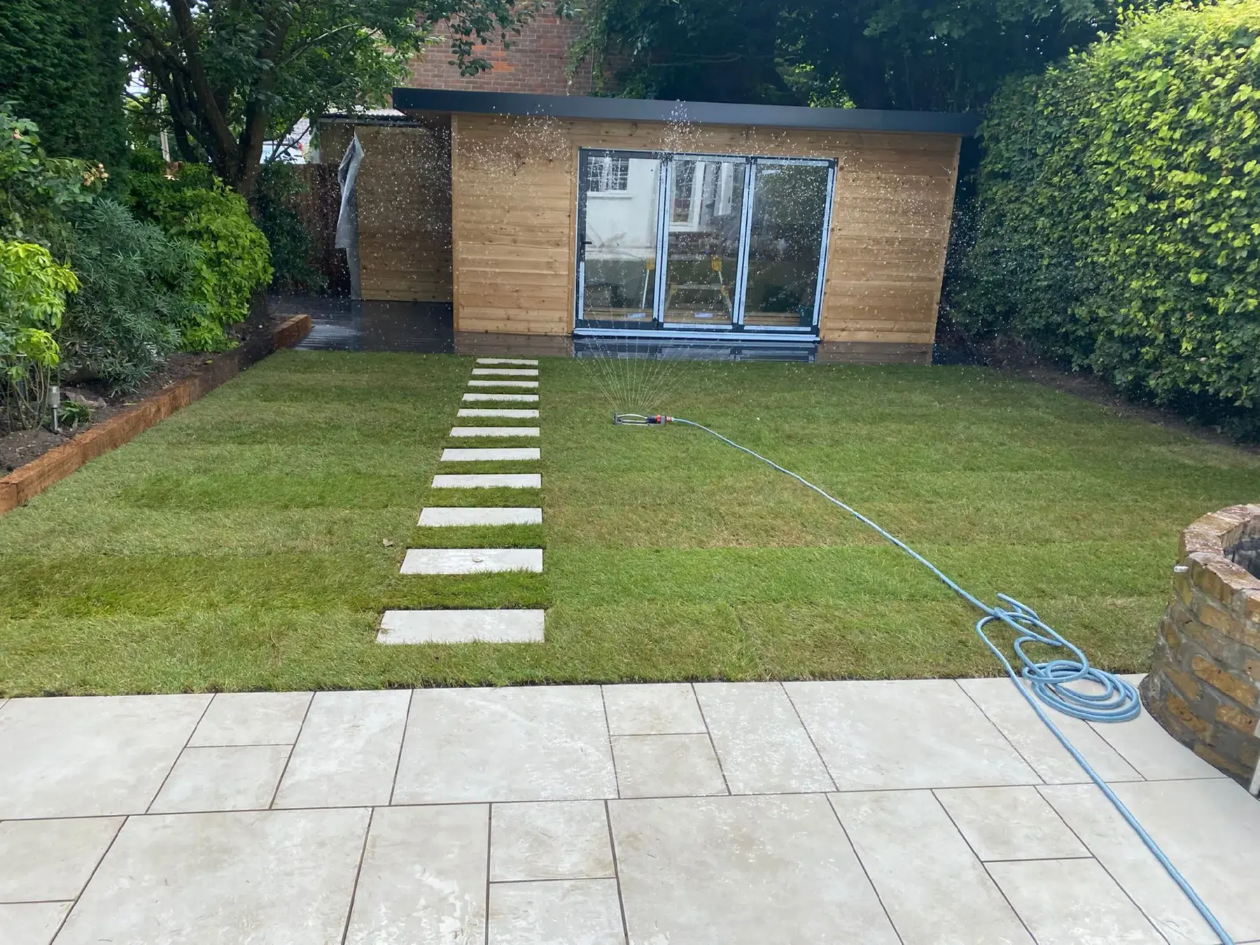 A new lawn with stepping stones to a garden office