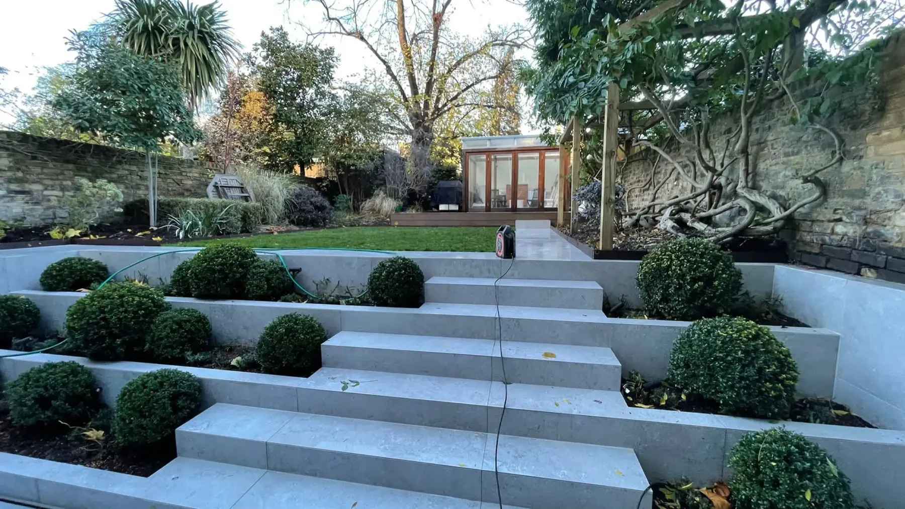Porcelain steps rising through a tiered garden with box balls